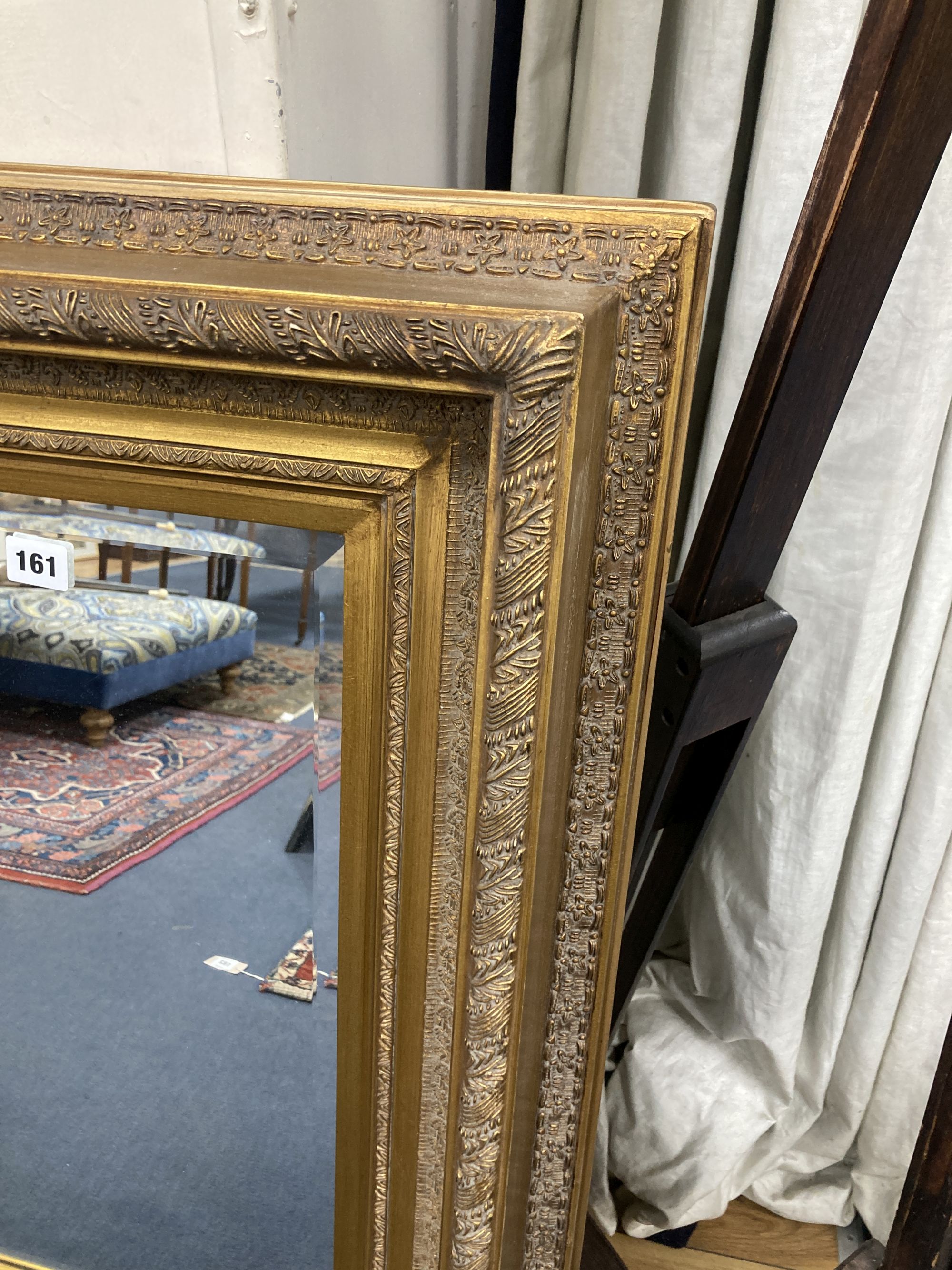 A gilt framed mirror, the base inset with a composition relief depicting putti at play, width 56cm, height 105cm